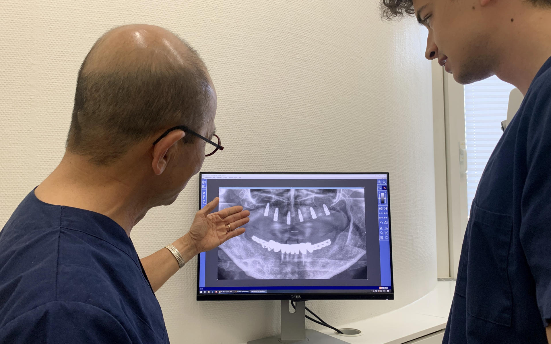 Zahnärzte Leuchtweis betrachten am Monitor ein Röntegnbild mit 6 Implantaten im Oberkiefer